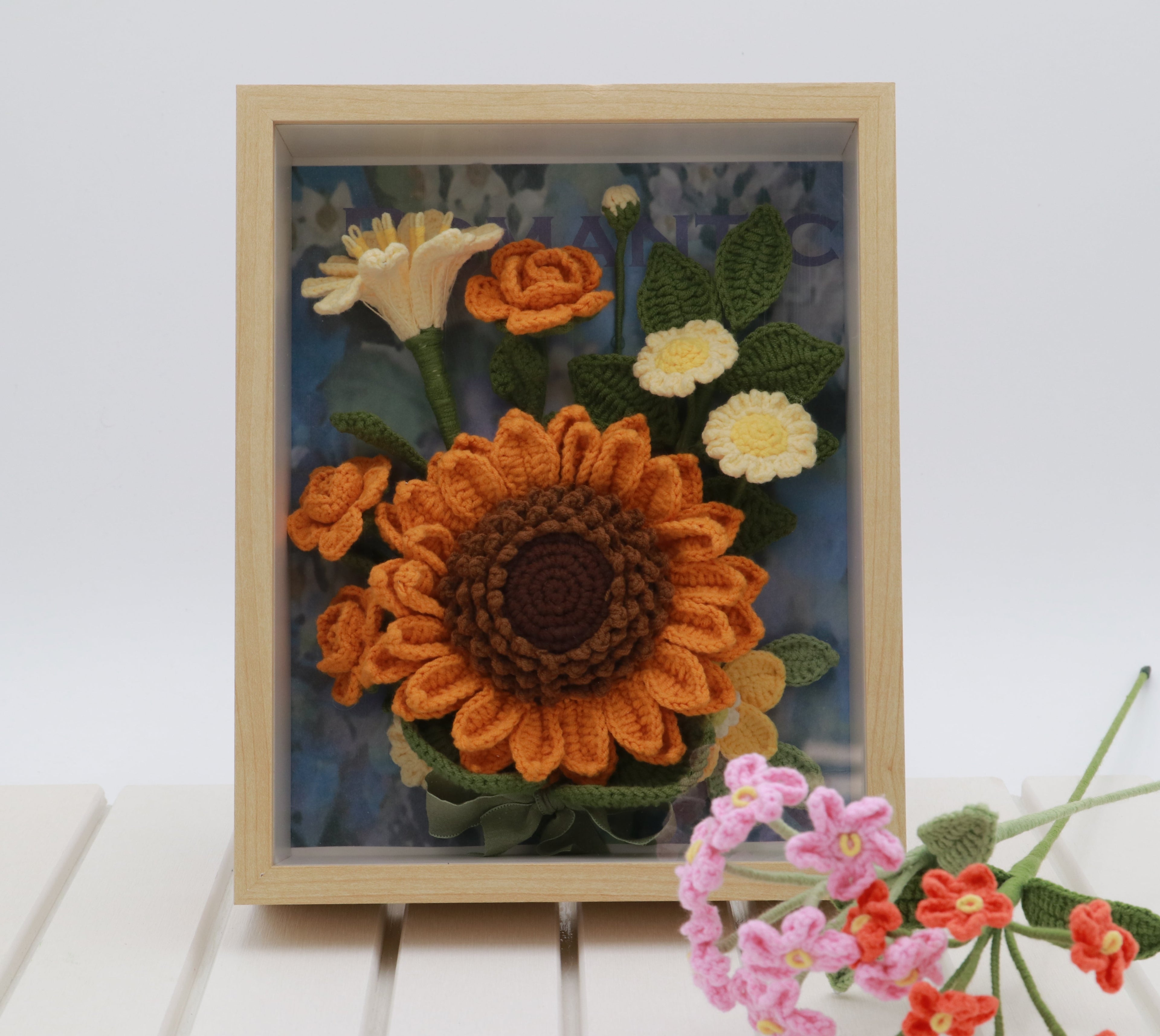Handmade sunflower crochet frame with orange and yellow flowers in a wooden shadow box
